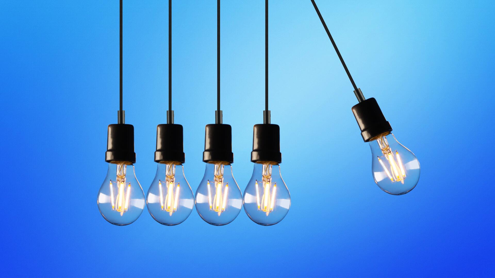 vier lampen hangen op een rij waar een vijfde tegenaan gaat botsen